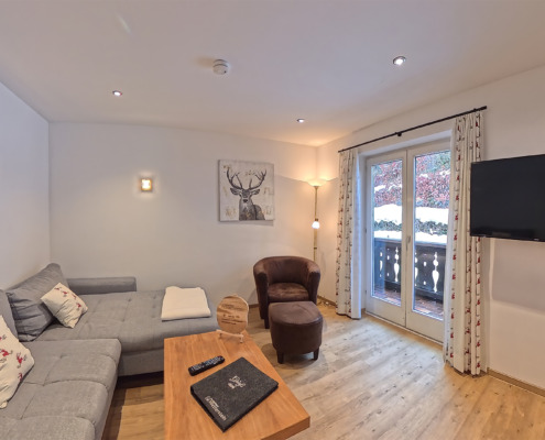 Der Wohnbereich mit Couch, Sessel, Tisch sowie Fernseher unserer Ferienwohnung "Waldblick" im Ferienhaus Wetterstein in Grainau direkt an der Zugspitze